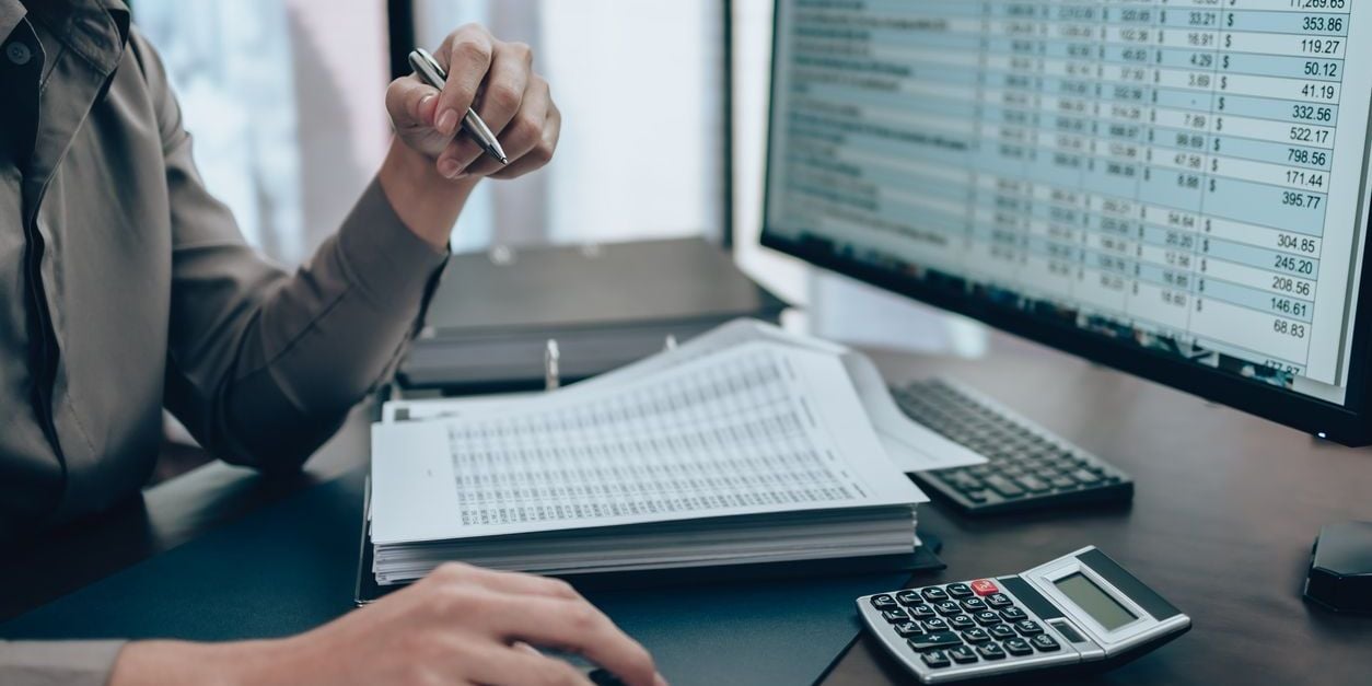 Calculating with Excel spreadsheet, paper, pen, and calculator.